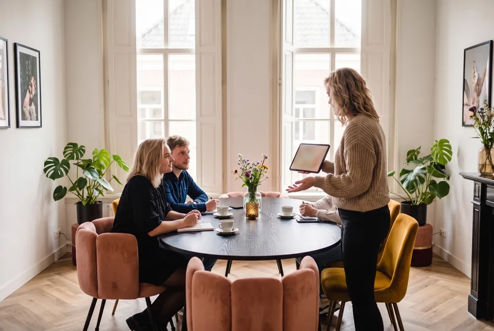 Aan de ovale tafel wordt de offerte doorgenomen met de gast erbij.