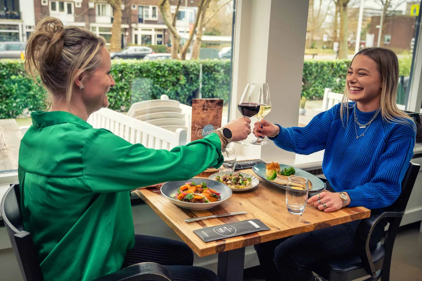 Twee gasten proosten aan een tafel in het restaurant