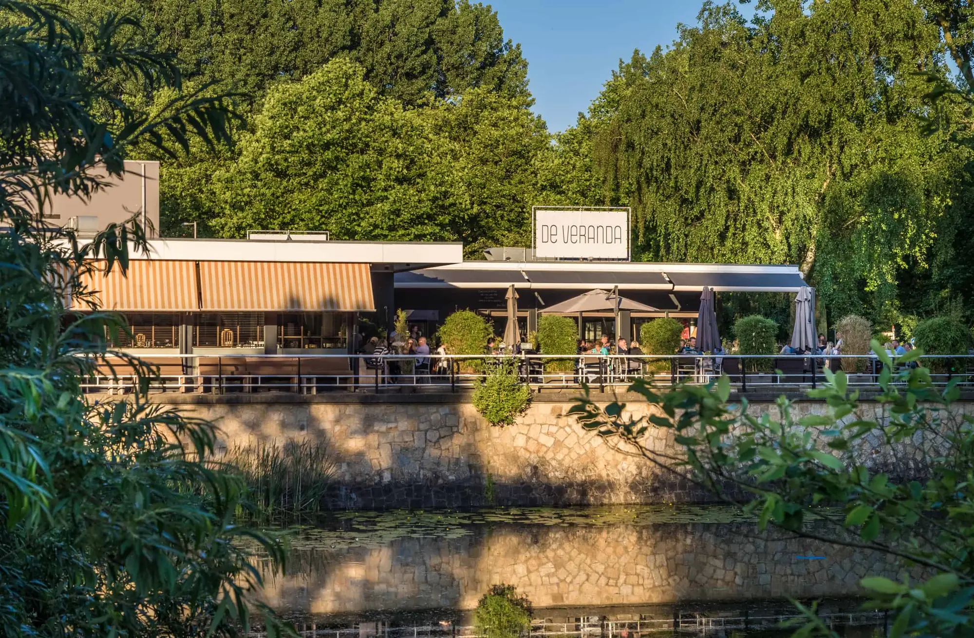 De Veranda aan de rand van het Amsterdamse Bos, gezien vanaf de overkant van het water, met het terras langs de gevel