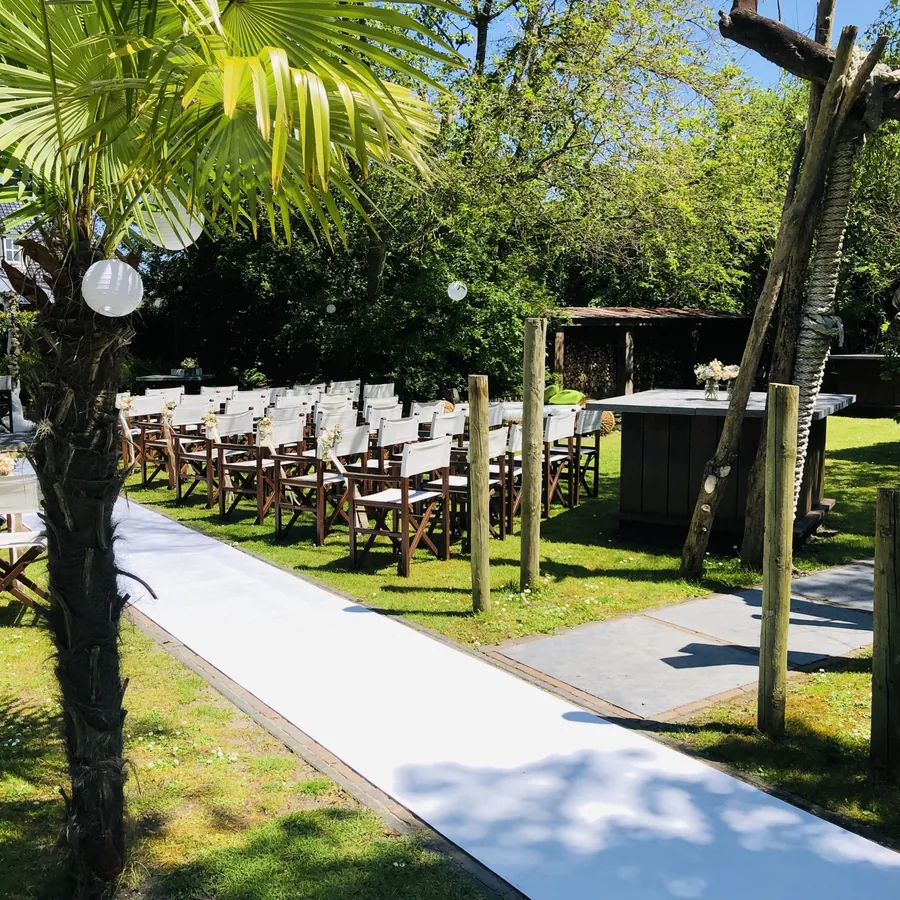 Het restaurant met terras en rieten parasols overdag, met palmen ernaast