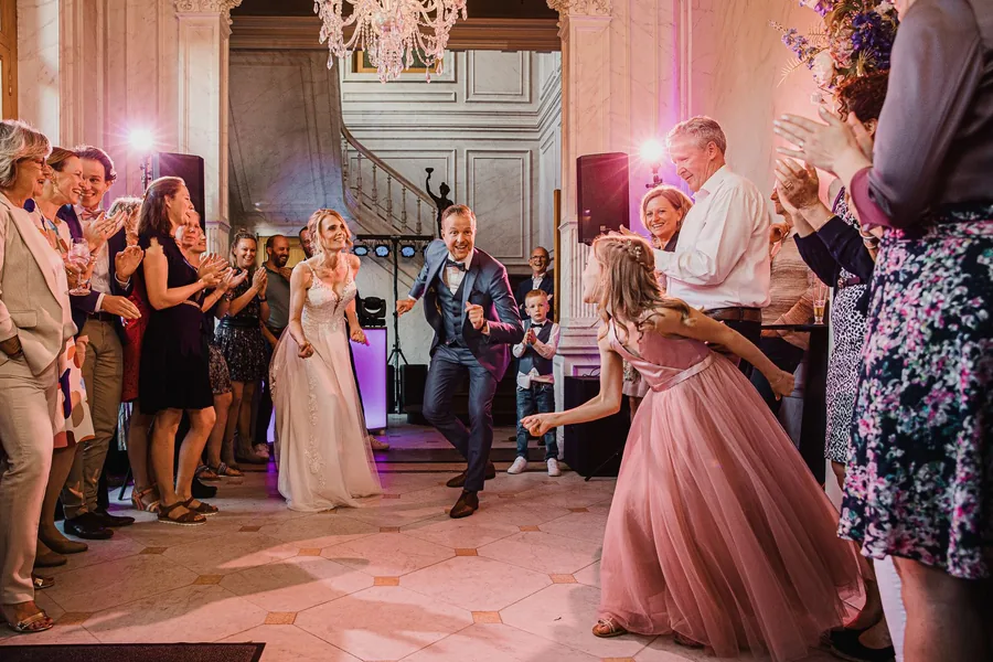 Het bruidspaar danst tussen de gasten in de salon