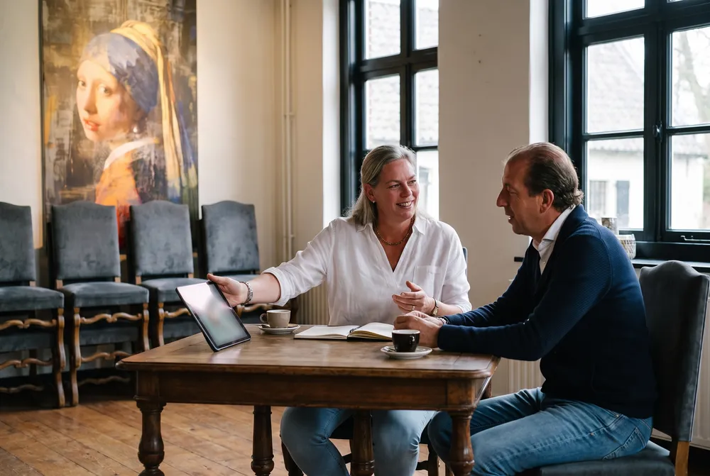Fabiënne en Jan-Willem aan tafel in de zaal, met een tablet tussen hen in