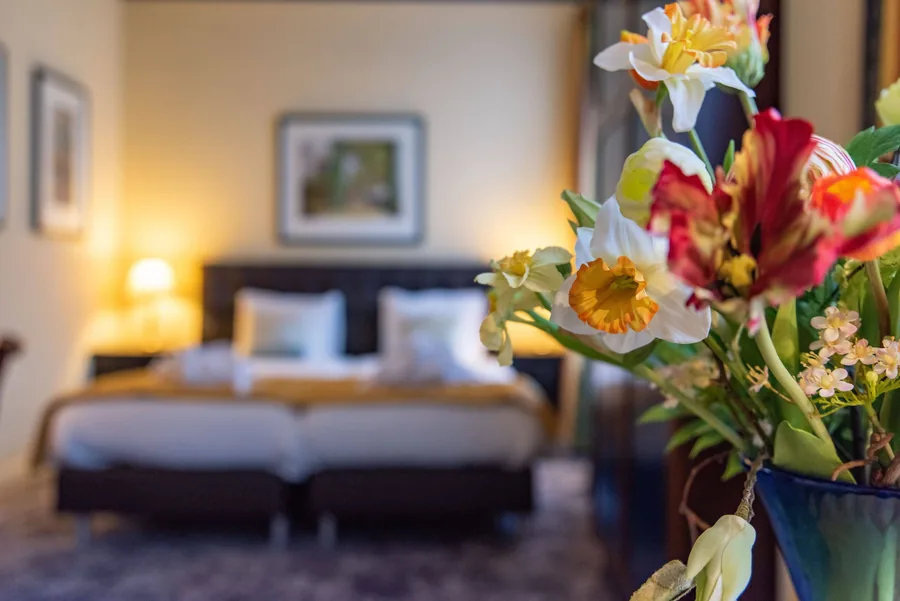 Een hotelkamer met opgemaakte bedden en een boeket bloemen op de voorgrond